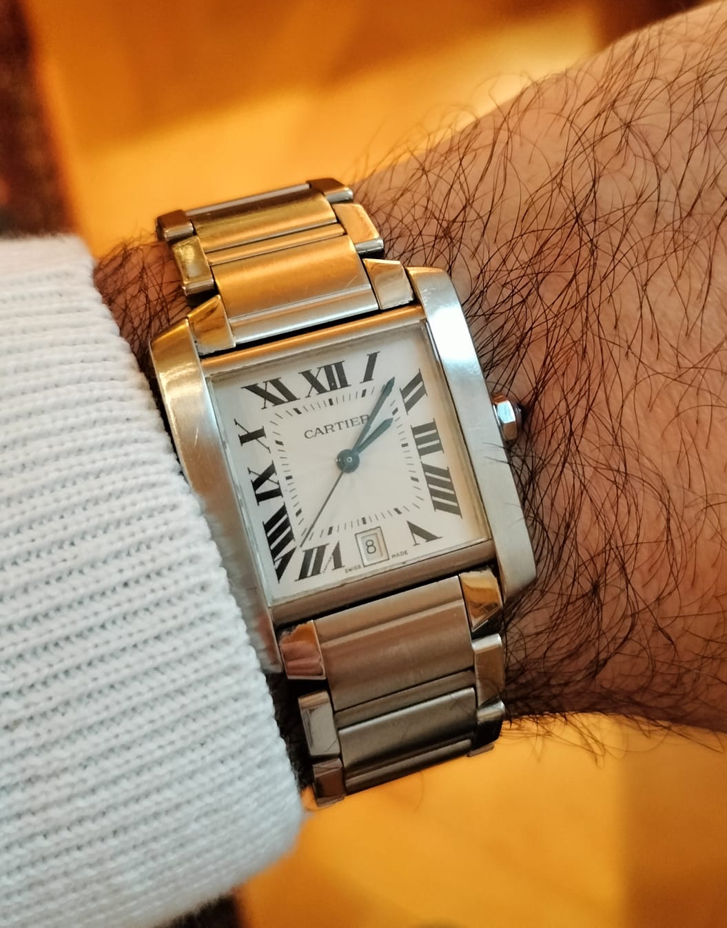 Rectangular Cartier Tank Française wristwatch with Roman numerals and a metal bracelet.
