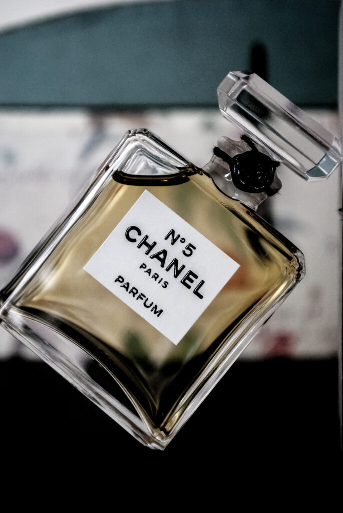 Angled glass Chanel N°5 Parfum bottle with pale amber perfume and a clear stopper.