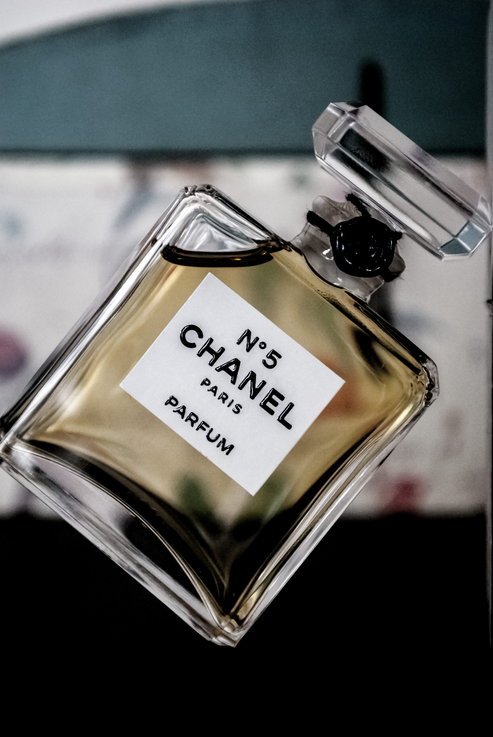 Angled glass Chanel N°5 Parfum bottle with pale amber perfume and a clear stopper.