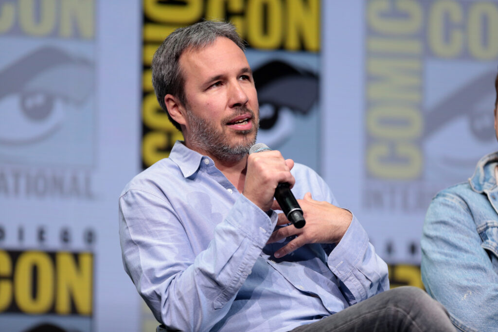 Denis Villeneuve holding a microphone at San Diego Comic-Con in 2017.