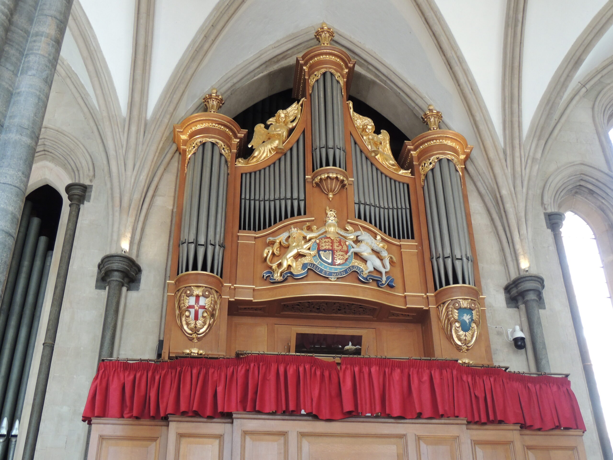 The Temple Church organ pipes and case above a red curtain.