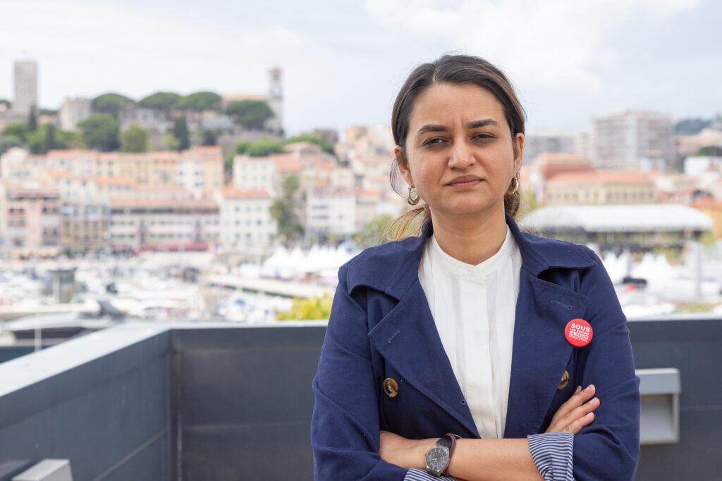 Payal Kapadia in a navy jacket with Cannes harbour behind her in 2024.