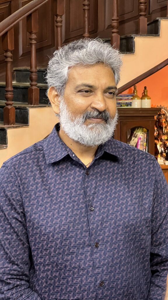 S. S. Rajamouli with grey hair and beard wearing a patterned blue shirt.
