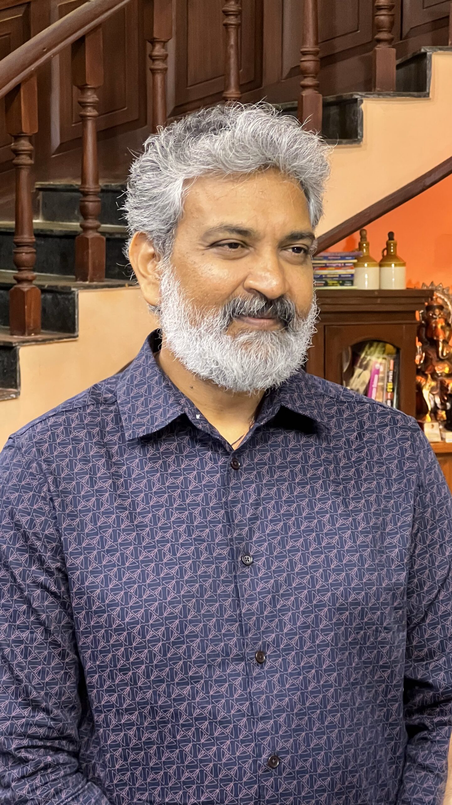 S. S. Rajamouli with grey hair and beard wearing a patterned blue shirt.